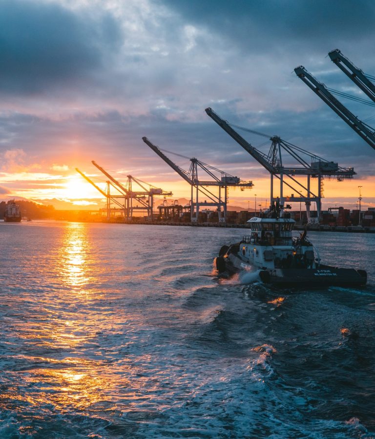 a panoramic shot of oil rigs at sea with a beautiful sunset in the background, under cloudy sky